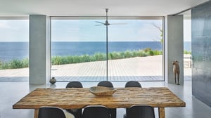 Utsikt mot hav gjennom store glassdører fra spiseplass