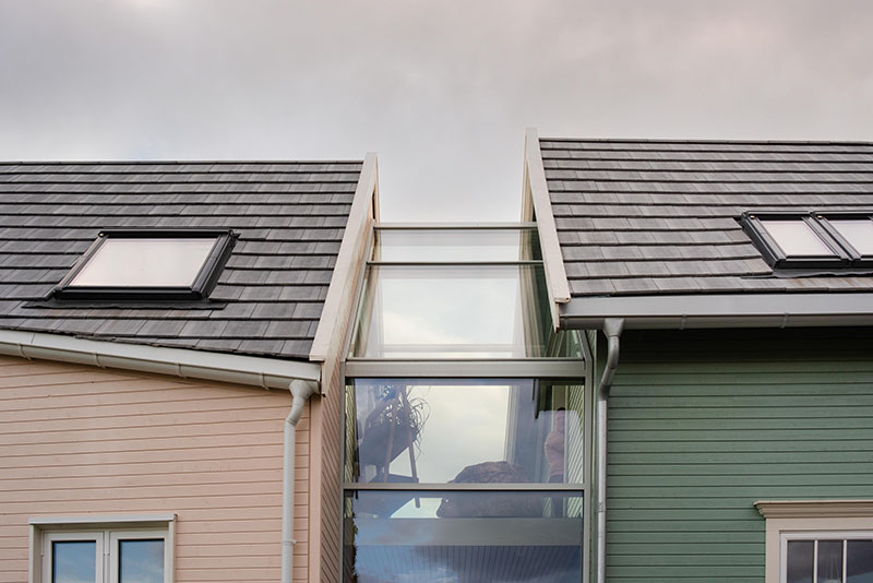 Øvre del av mellombygningen i glass, med fokus på glasstaket, med de to husdelene på hver side.