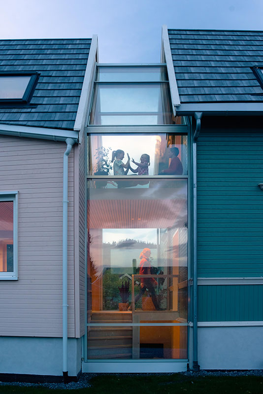 Mellombygg i glass med glasstak som forbinder en eksisterende villaen til høyre med et nytt tilbygg til venstre.