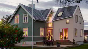 Enebolig i Trondheim, med det nye tilbygget i glass og tre på gavlveggen, sett i skumringen med varmt lys innenfra.
