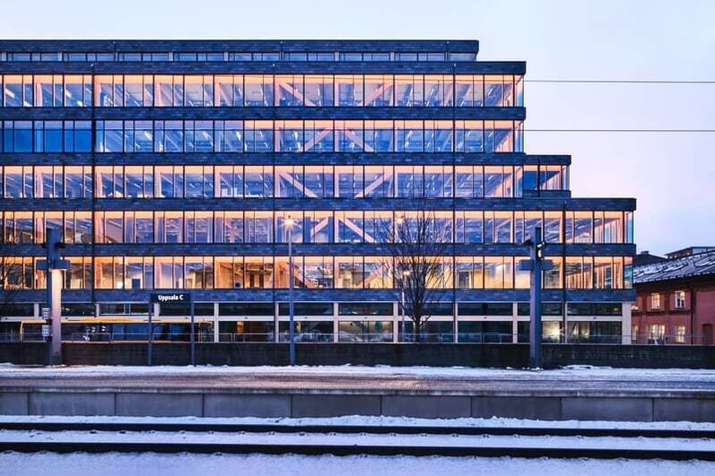 Magasin X i Uppsala – sju etasjer bærekraftig kontorbygg i tre med panoramavindu og rødt skifer-bånd